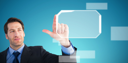 Confident businessman pointing at something against abstract blue backgroundの写真素材