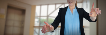 Young businesswoman working on imaginary interface against foyer area with elevatorの写真素材