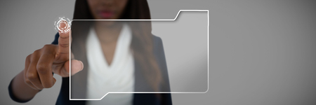 Young businesswoman touching imaginary screen against grey backgroundの写真素材