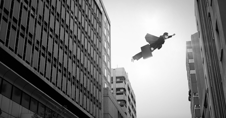 Digital composite of businesswoman flying over surreal city buildings perspectiveの写真素材