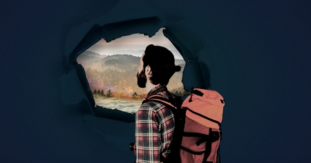 Digital composite of hiking adventurer man looking through surreal paper hole at nature landscapeの写真素材