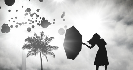 Digital composite of women holding umbrella silhouette with tropical storm and circlesの写真素材