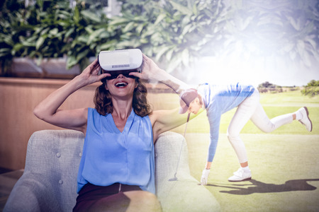 Female golfer picking up golf ball  against happy executive using virtual reality 3D headsetの写真素材