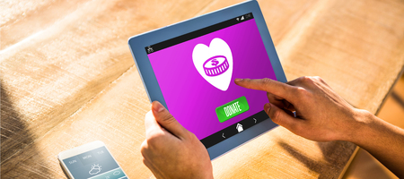 Vector icon of donation against over shoulder view of casual man using tabletの写真素材