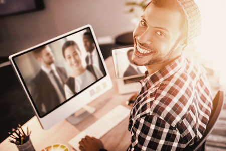Portrait of man smiling while sitting by computer against happy businesswoman in officeの写真素材