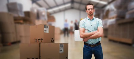Composite 3D image of serious warehouse manager standing with arms crossed against warehouse...