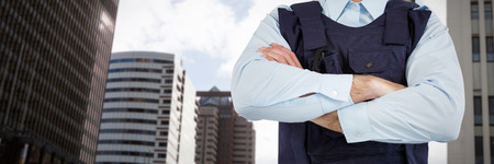 Mid section of security officer standing with arms crossed against view of modern office buildingの写真素材