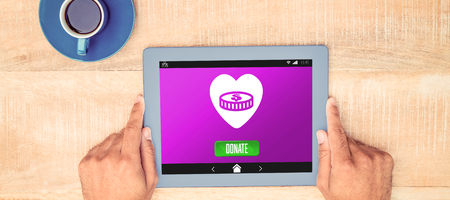 Vector icon of donation against hand holding on digital tablet over table by coffeeの写真素材