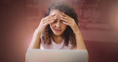Digital composite of Woman working on laptop stressed holding headの写真素材