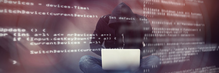 Male hacker using laptop against code