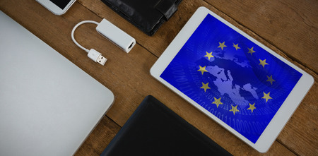 Various electronic gadgets on wooden plank against european union flag with binary codesの写真素材