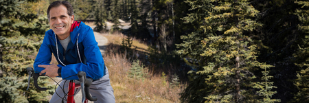 Digital composite of senior man with his bike against road through forestの写真素材
