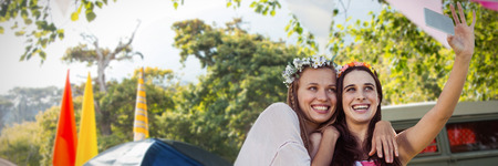 Smiling friends taking a selfie against empty campsite at music festivalの写真素材
