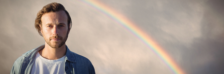 Portrait of handsome man against rainbow in a dark sky above the green hillの写真素材