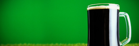 Close-up of green beer mug on grass for St Patricks Day against green background