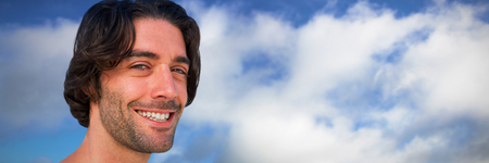 Portrait of smiling young man against white background against blue sky with cloudsの写真素材