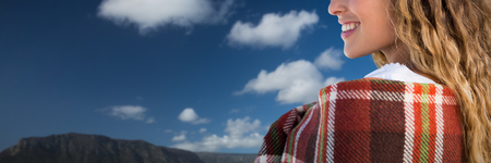 Smiling beautiful woman wrapped in blanket against boats moored at harborの写真素材