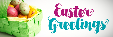 Easter greeting against speckled easter eggs in a basketの写真素材