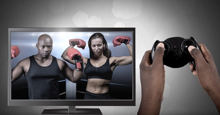 Digital composite of Hands holding gaming controller  with boxing fighters on television