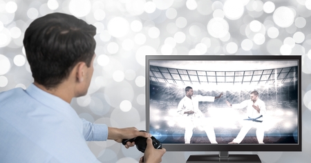 Digital composite of Hands holding gaming controller  with martial arts fighters on television