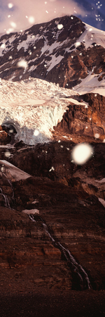 Snow falling against snow capped mountains on a sunny dayの写真素材