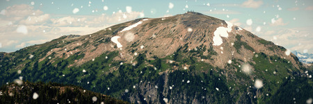 Snow falling against snowcapped mountain during winterの写真素材