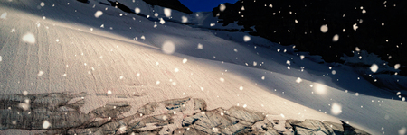 Snow falling against glacier on mountain slopeの写真素材