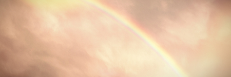 Beautiful rainbow in a dark sky above the green hillの写真素材