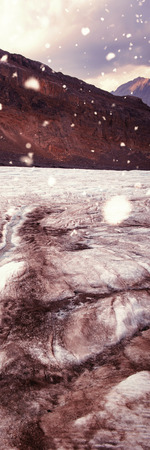 Snow falling against mountains on a sunny dayの写真素材