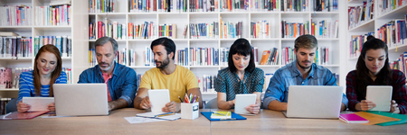 Business people working at table against teacher reading books to her studentsの写真素材