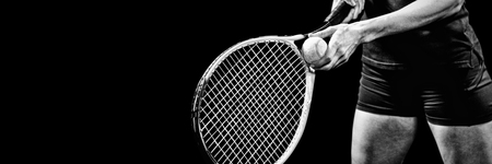 Tennis player holding a racquet ready to serve on black background