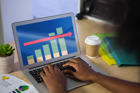 Business graph and chart against cropped hands of man using laptop at tableの写真素材