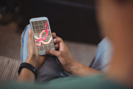 Business graph and chart against man using mobile phone in living roomの写真素材