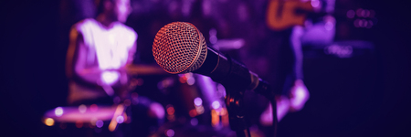Close up of microphone with performers in backgroundの写真素材