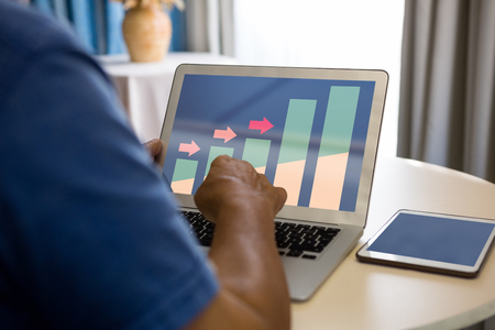 Business graph and chart against cropped hand of senior man using laptop in nursing homeの写真素材