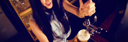 Female bartender preparing drink at counter in bar