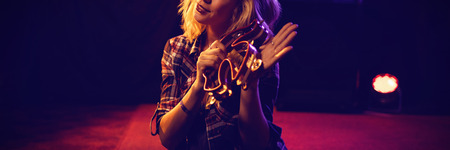Portrait of young woman playing tambourine at concert in nightclubの写真素材