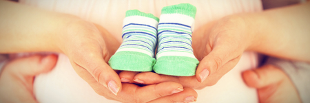 Close-up of pregnant woman holding baby shoesの写真素材