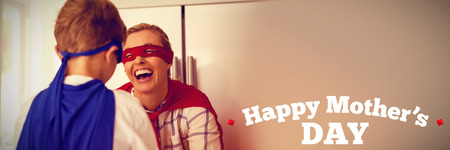 mothers day greeting against mother and son pretending to be superhero in the kitchenの写真素材