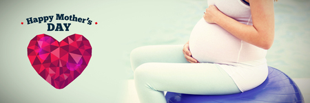 happy mothers day against side view of pregnant woman sitting on exercise ballの写真素材