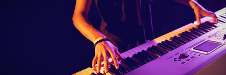 Mid section of male musician playing piano in illuminated nightclubの写真素材