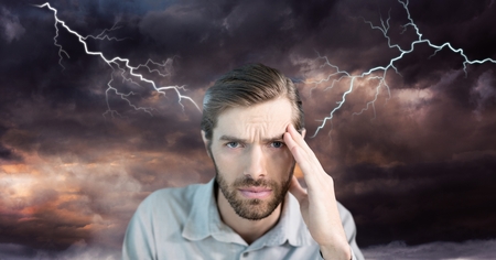 Digital composite of Lightning strikes and stressed man with headache holding headの写真素材