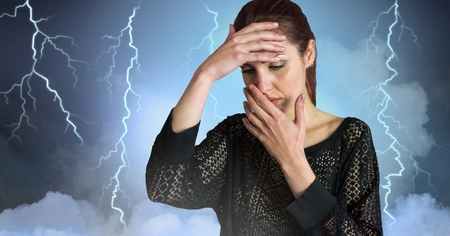 Digital composite of Lightning strikes and stressed woman with headache holding headの写真素材