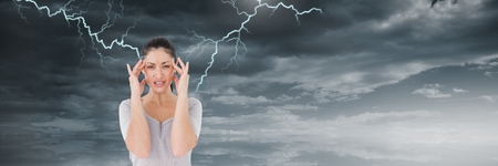 Digital composite of Lightning strikes and stressed woman with headache holding headの写真素材