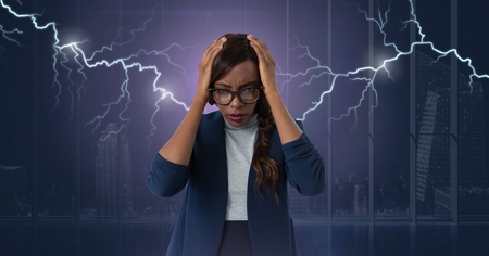 Digital composite of Lightning strikes and stressed woman with headache holding headの写真素材