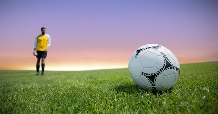 Digital composite of Soccer player on grass with skyの写真素材