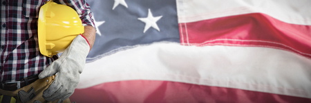 Mid-section of construction worker against full frame of wrinkled american flagの写真素材