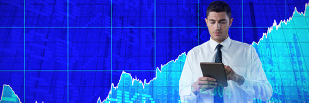 Business man using a tablet against stocks and shares