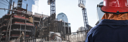 Back of Firefighter against low angle view of cranes by buildings