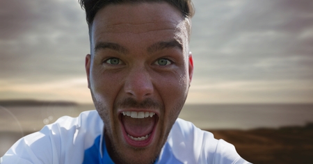 Digital composite of Excited man opening mouth wide with landscapeの写真素材